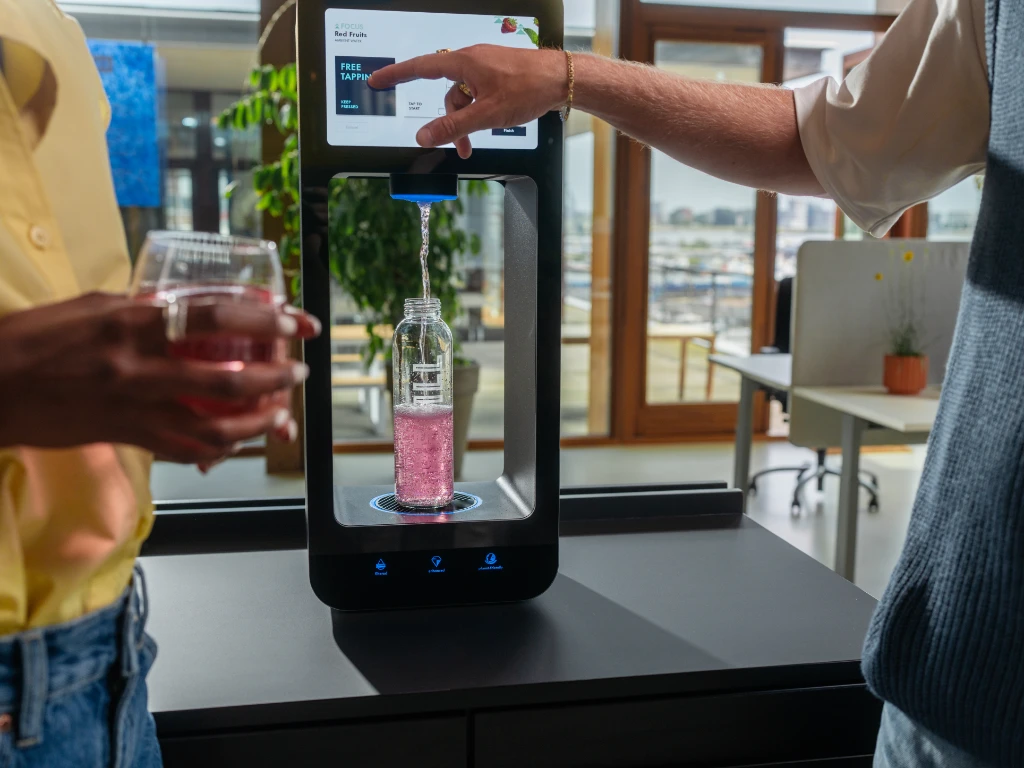 Two people using Aquablu touchscreen water dispenser to fill a bottle with flavoured water